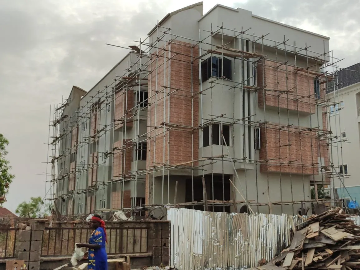 Side of the block with cladding in progress, materials stacked behind a site fence
