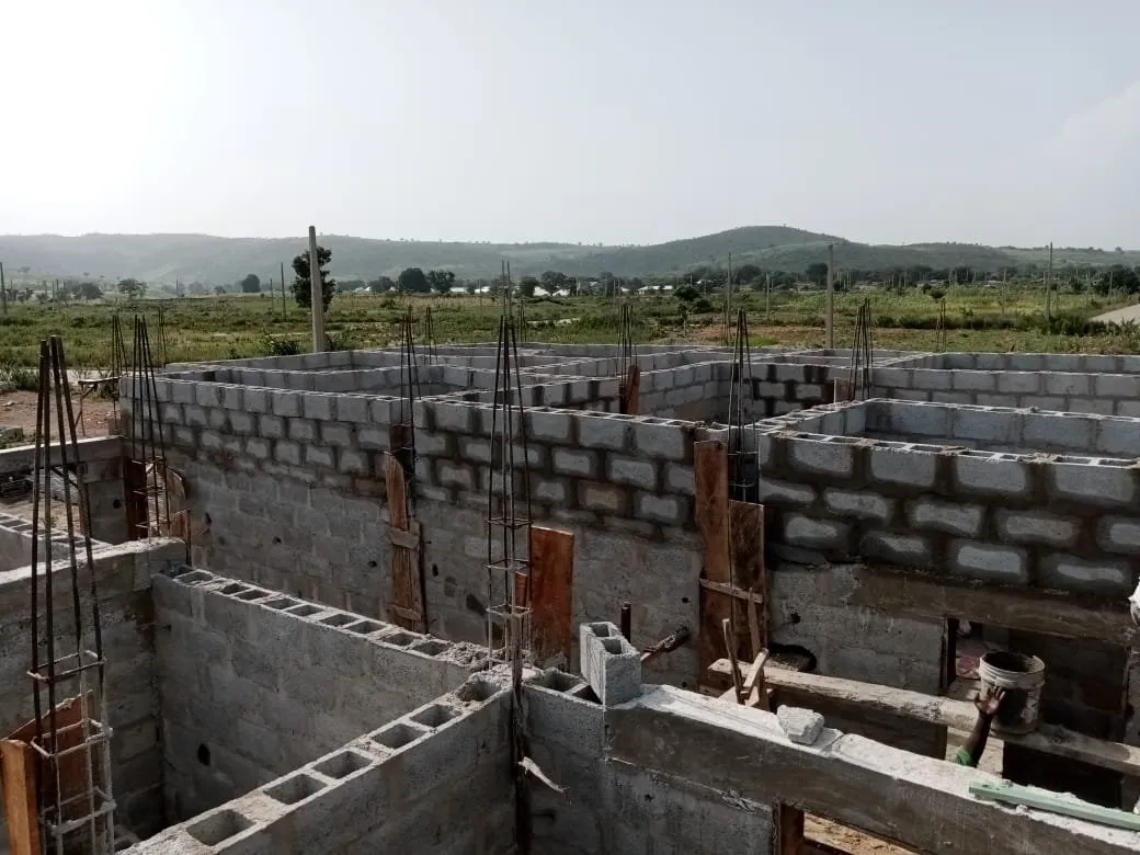 Blockwork walls rising on a ground-floor slab, starter bars projecting from the columns
