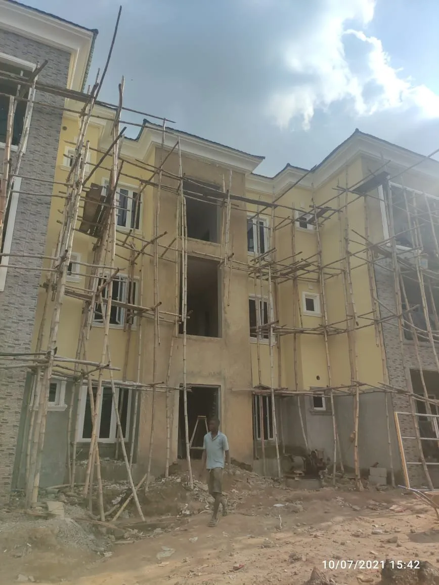 Front of the block in scaffolding, a worker walking past at ground level