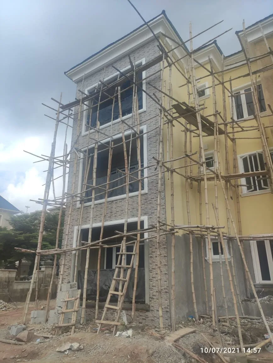 Stair bay of the block with stone cladding on the lower floors, timber scaffolding and a ladder
