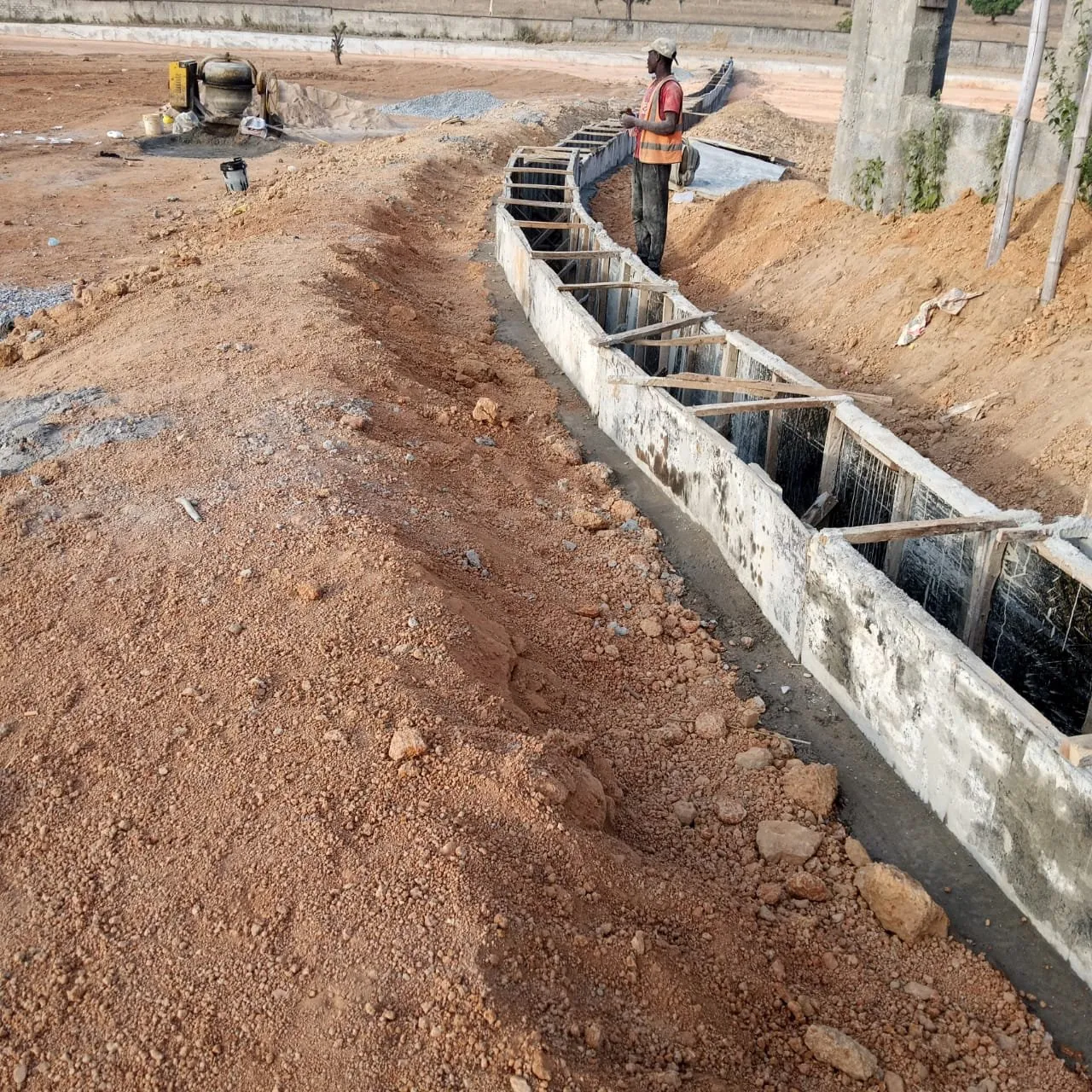 Concrete channel under construction with formwork, a worker standing beside it