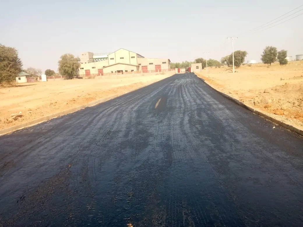 Finished asphalt road leading towards buildings